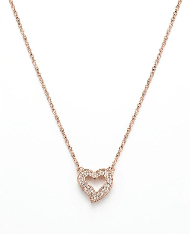 A delicate rose gold chain necklace featuring a small open heart pendant with a border of tiny clear stones, set against a plain white background.