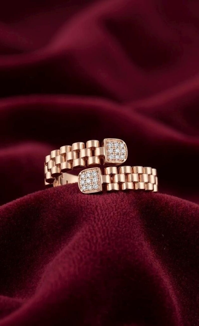 Rose gold plated watch-link ring with two square pave CZ ends on deep red velvet fabric