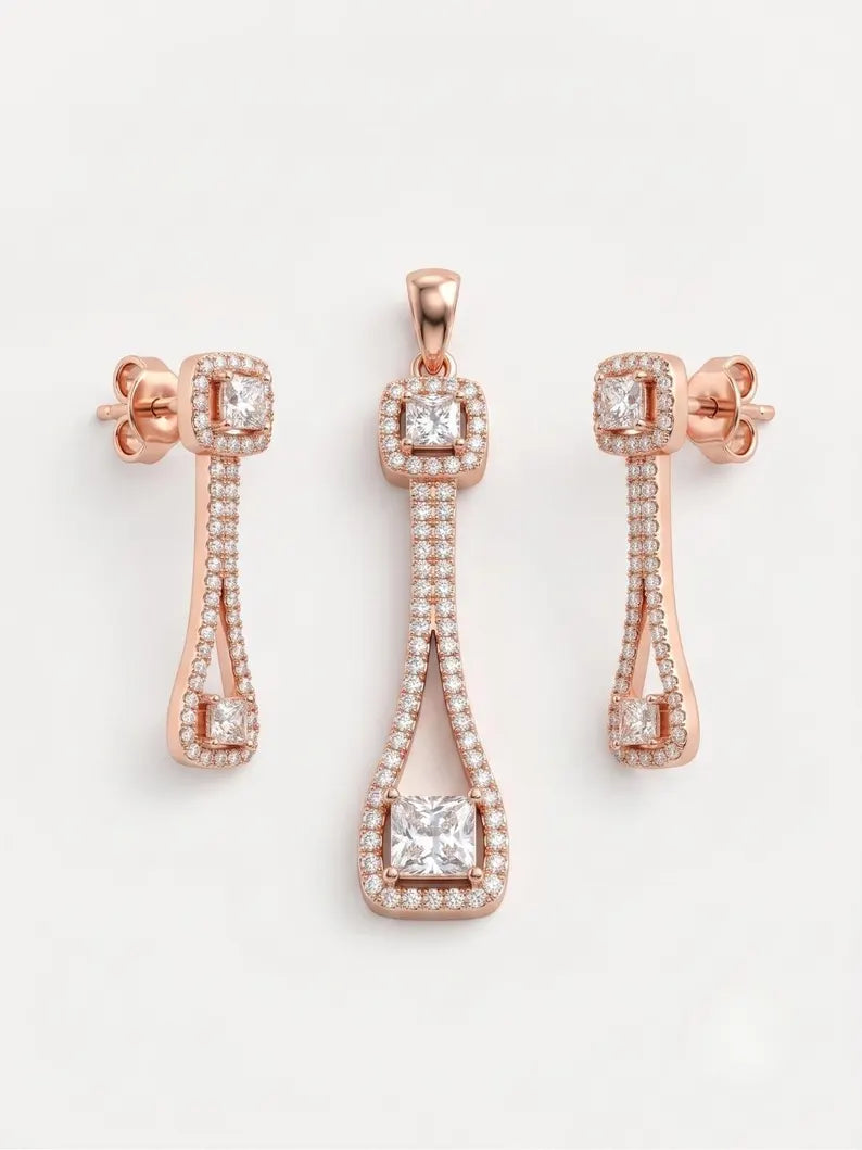 Rose gold jewelry set featuring a pendant and two matching drop earrings, each adorned with clear gemstones on a light gray background.