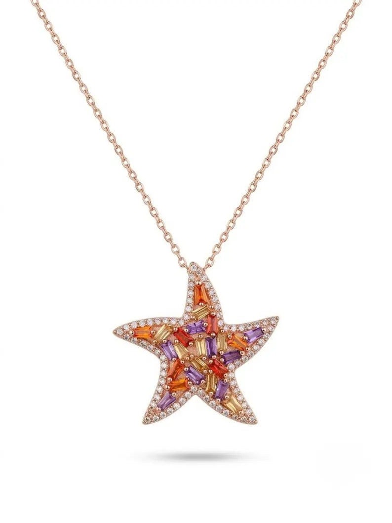 A rose gold starfish pendant necklace featuring a vibrant array of orange, red, and purple baguette-cut gemstones, accented with small clear stones, shown on a white background.
