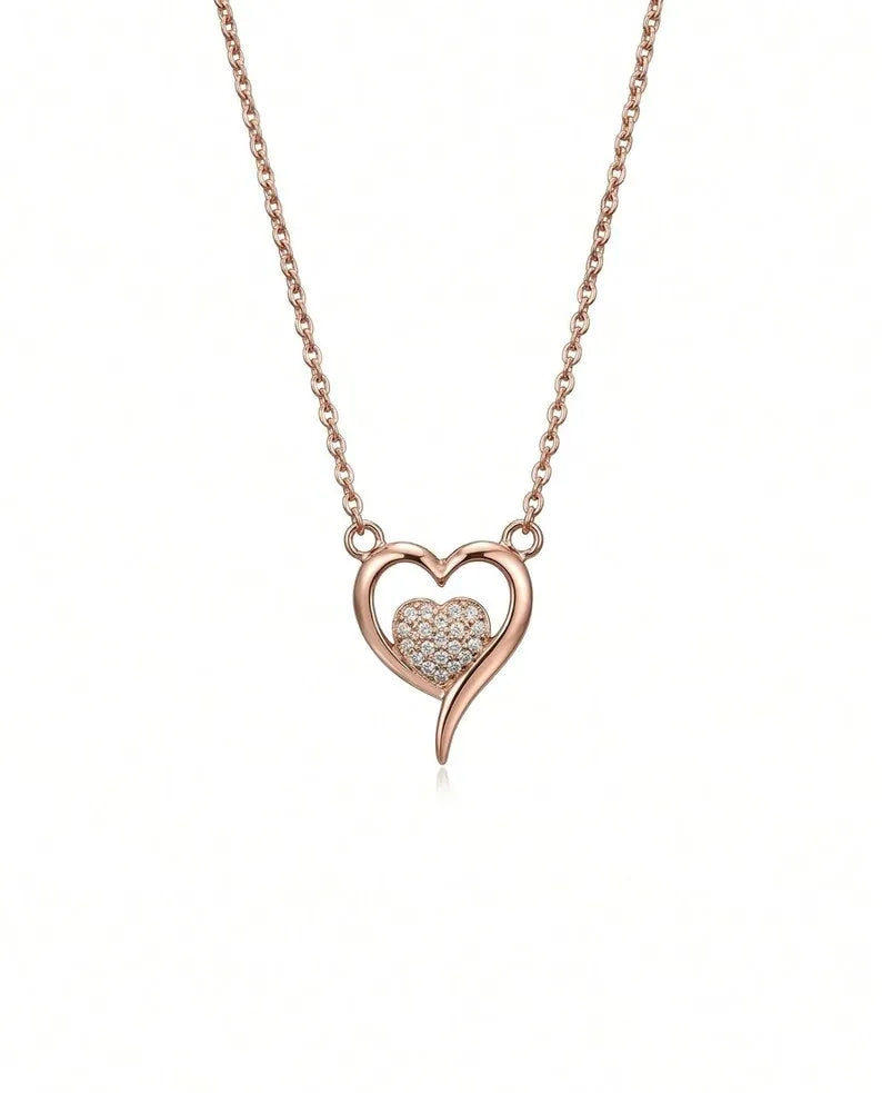A rose gold heart pendant necklace featuring a pavé-set heart in the center of an open heart outline, suspended from a delicate cable chain on a white background.
