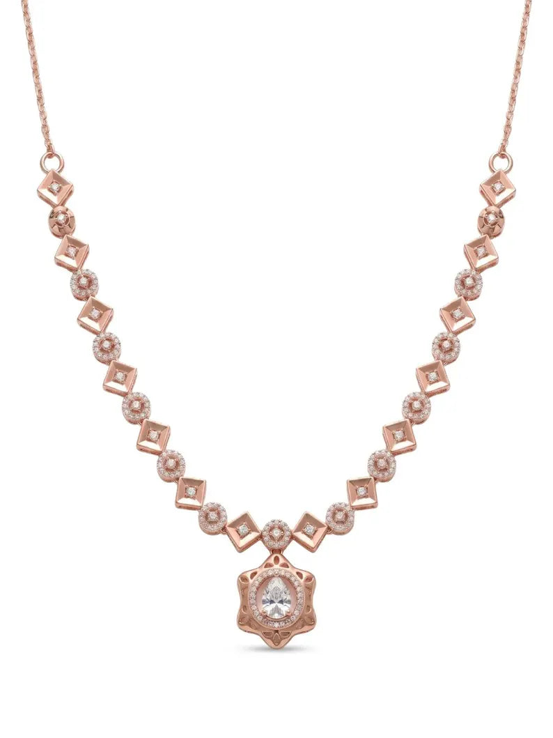 A rose gold necklace featuring a delicate chain with repeating diamond-shaped and round pavé settings, culminating in a central starburst pendant with a clear round gemstone, shown on a plain white background.