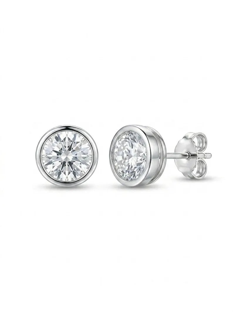 A pair of round bezel-set diamond stud earrings in silver-tone metal, shown from the front and side on a clean white background.