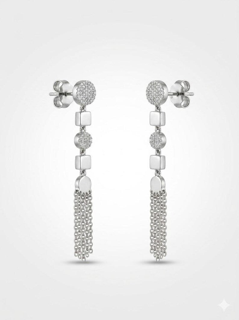 A pair of silver-toned drop earrings with circular pavé studs, square spacer beads, and dangling chain fringe, shown on a light gray background.