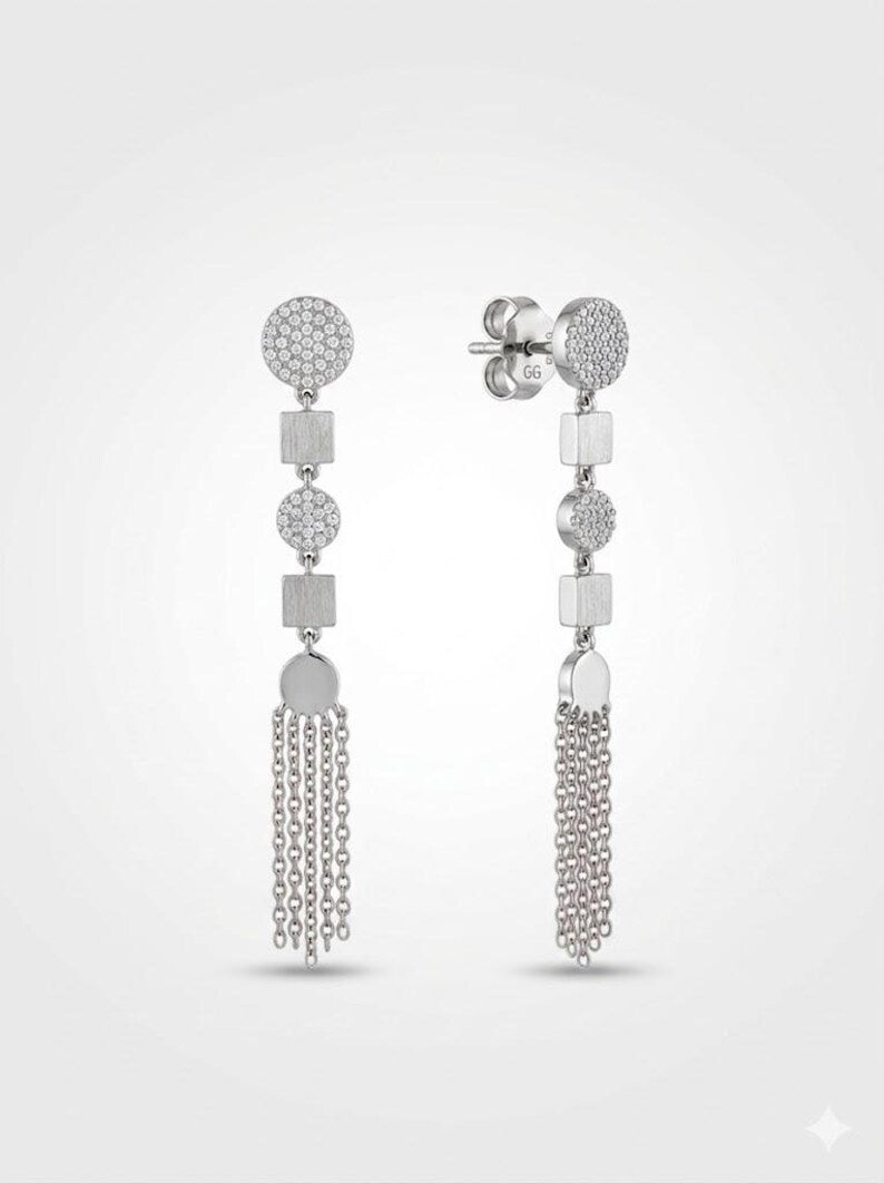 A pair of silver-toned dangle earrings with circular pavé studs, geometric square and oval links, and cascading chain fringe, shown on a light gray background.