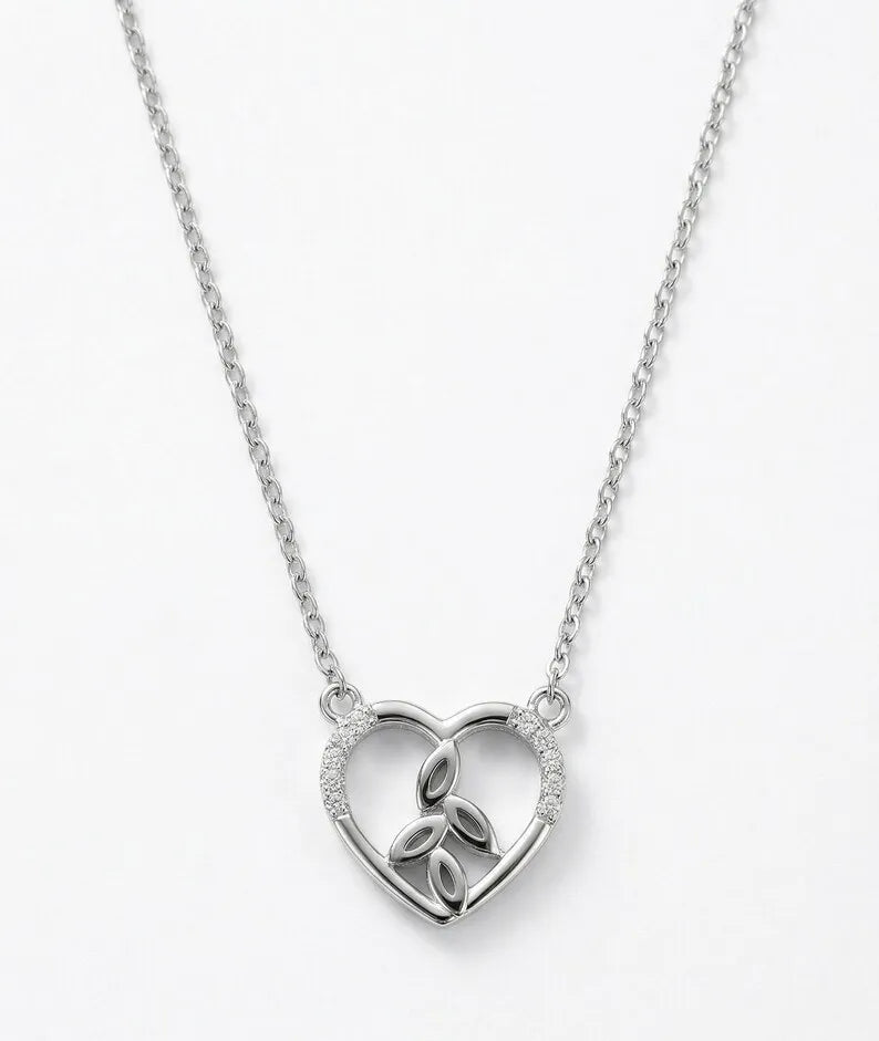 A silver heart-shaped pendant necklace featuring a triquetra knot design in the center and small clear stones along the left curve, shown on a white background.