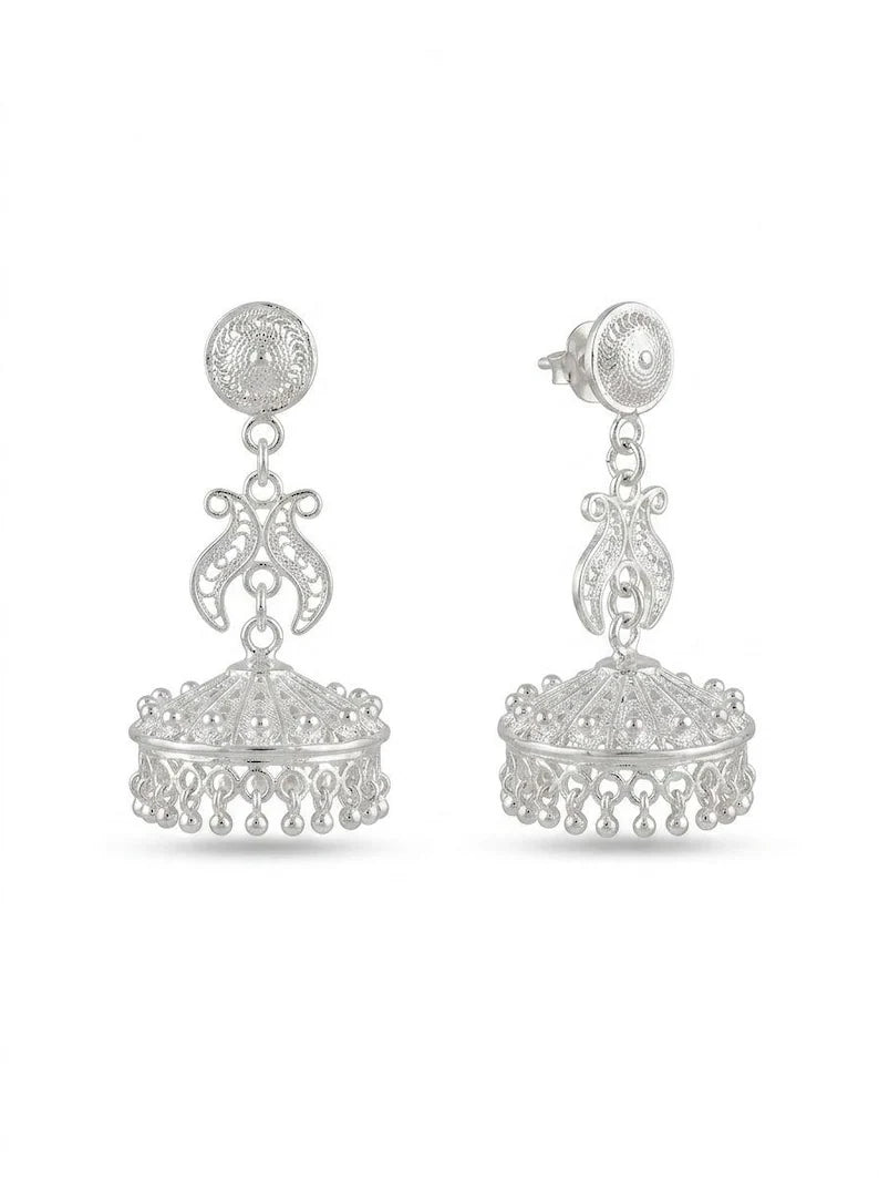 A pair of silver-toned traditional Indian jhumka earrings with intricate filigree work and dangling bell-shaped charms, shown against a plain white background.