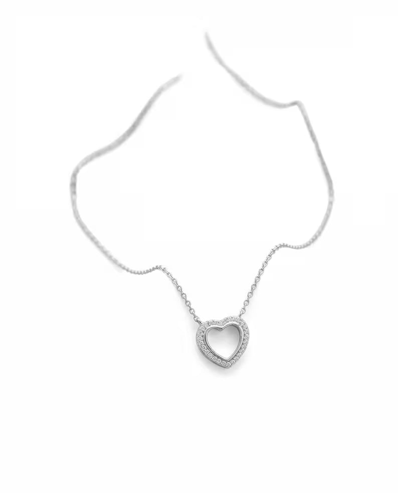 A silver-toned open heart pendant necklace on a delicate chain, displayed against a clean white background.