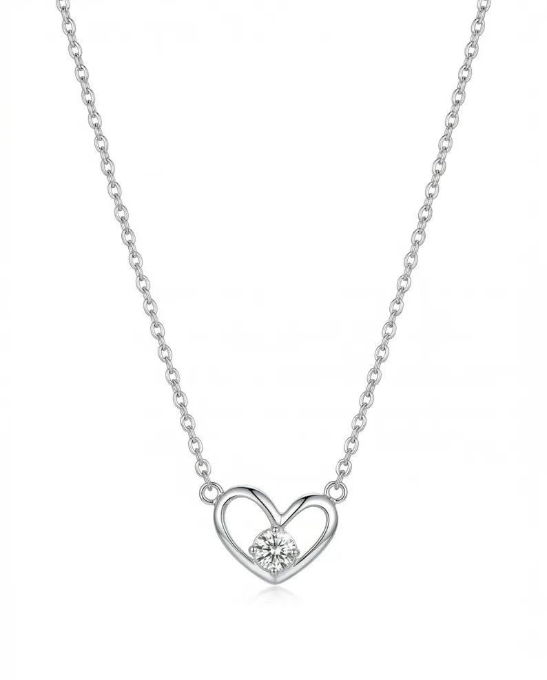 A silver chain necklace with a heart-shaped pendant featuring a small clear gemstone in the center, shown against a plain white background.