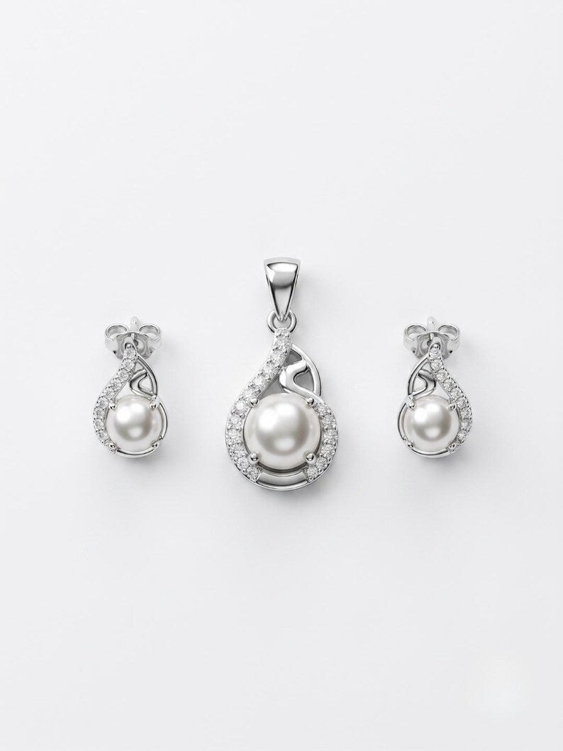 A jewelry set featuring a pendant and matching stud earrings in silver-tone metal with white freshwater pearls and small clear stones, displayed on a clean white background.