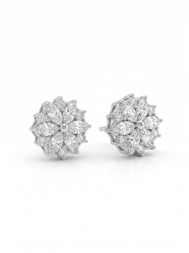 A pair of silver-toned stud earrings with a floral snowflake design Pair of marquise cluster stud earrings with clear marquise and round-cut gemstones, shown on a clean white background.
