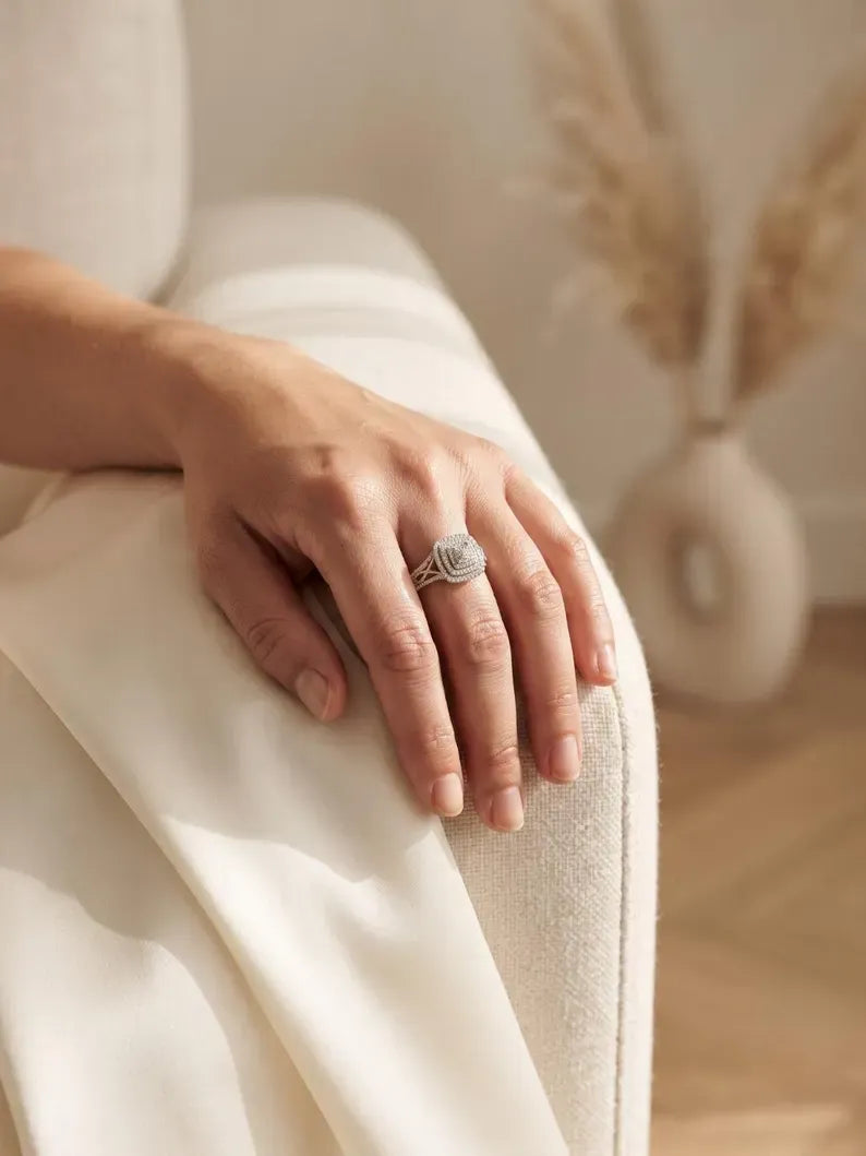 Hand resting on linen armchair wearing sterling silver square halo statement ring