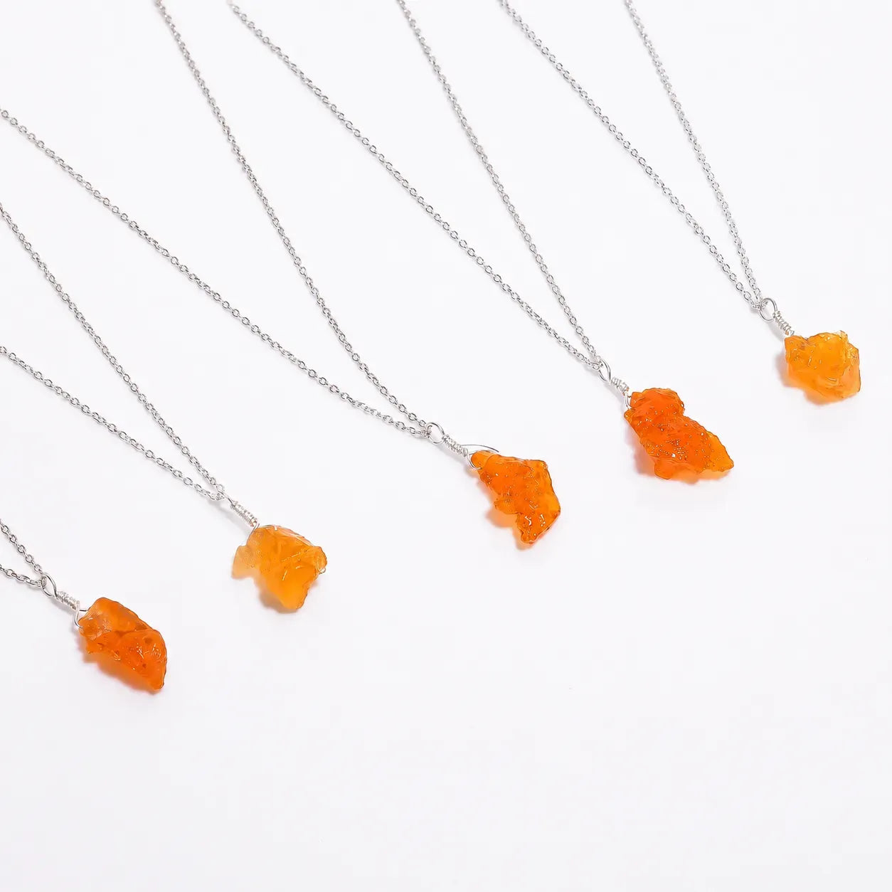 Orange stone necklaces on silver chains against a white background