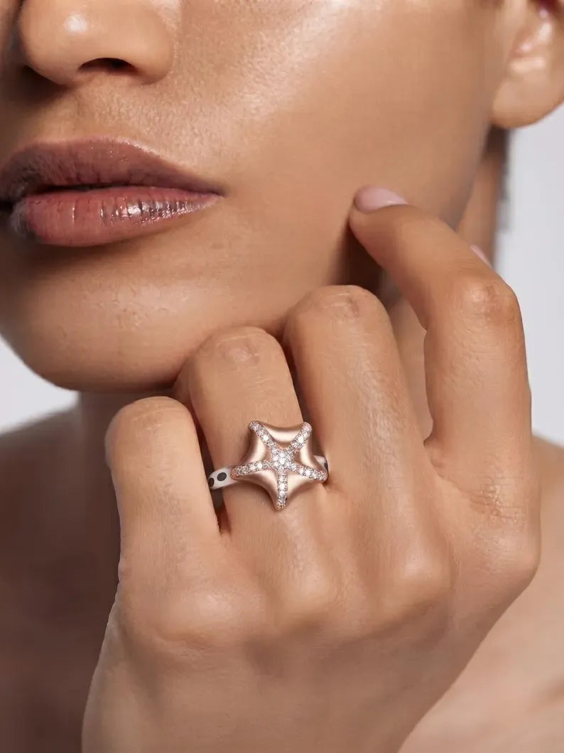 Woman showcasing a rose gold plated CZ starfish ring, part of sterling silver rings for women.