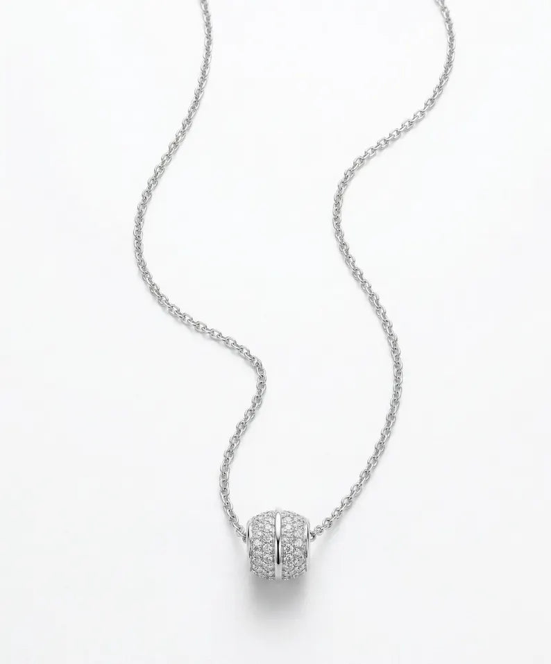 A silver-toned chain necklace with a pavé-set cylindrical pendant on a clean white background.