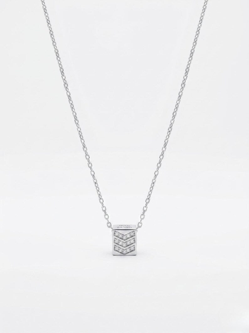 A silver-toned necklace featuring a small square pendant adorned with pavé-set clear stones, suspended from a delicate cable chain against a plain white background.