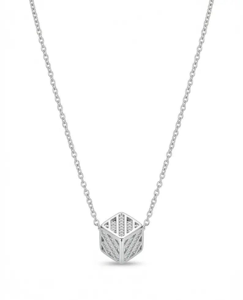 A silver geometric cube pendant necklace with openwork detailing, suspended from a delicate silver cable chain against a plain white background.