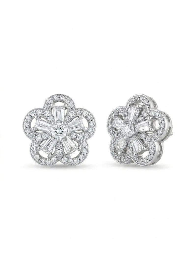 A pair of silver-toned flower-shaped stud earrings set with clear baguette and round-cut stones, shown from both front and side angles on a white background.