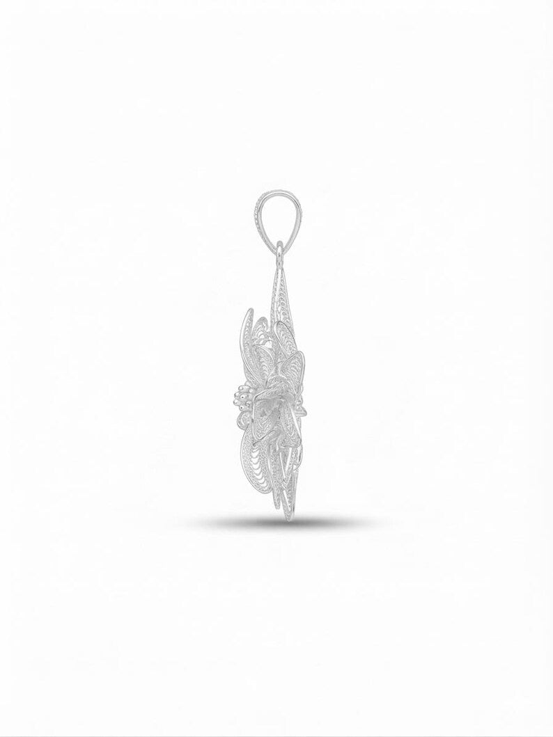 A silver-toned filigree pendant with an intricate openwork design and a circular loop at the top, shown against a plain white background with a soft shadow below.