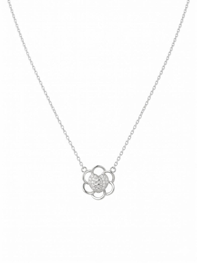 A delicate silver chain necklace featuring a flower-shaped pendant with a textured, diamond-like center and openwork petals, shown against a plain white background.