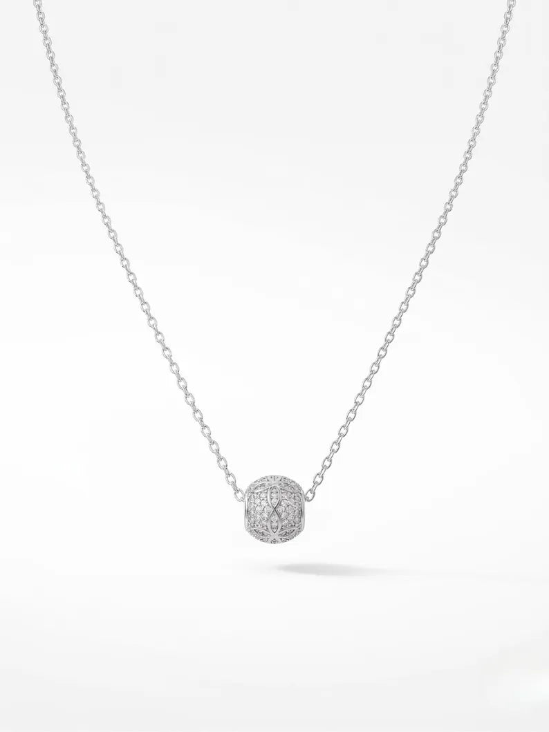 A delicate silver chain necklace featuring a small, round pavé-set pendant with clear stones, displayed against a clean white background.