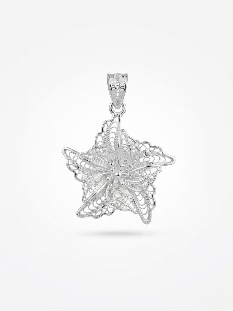A silver filigree pendant shaped like a snowflake or starburst, suspended from a matching bail, shown against a clean white background.