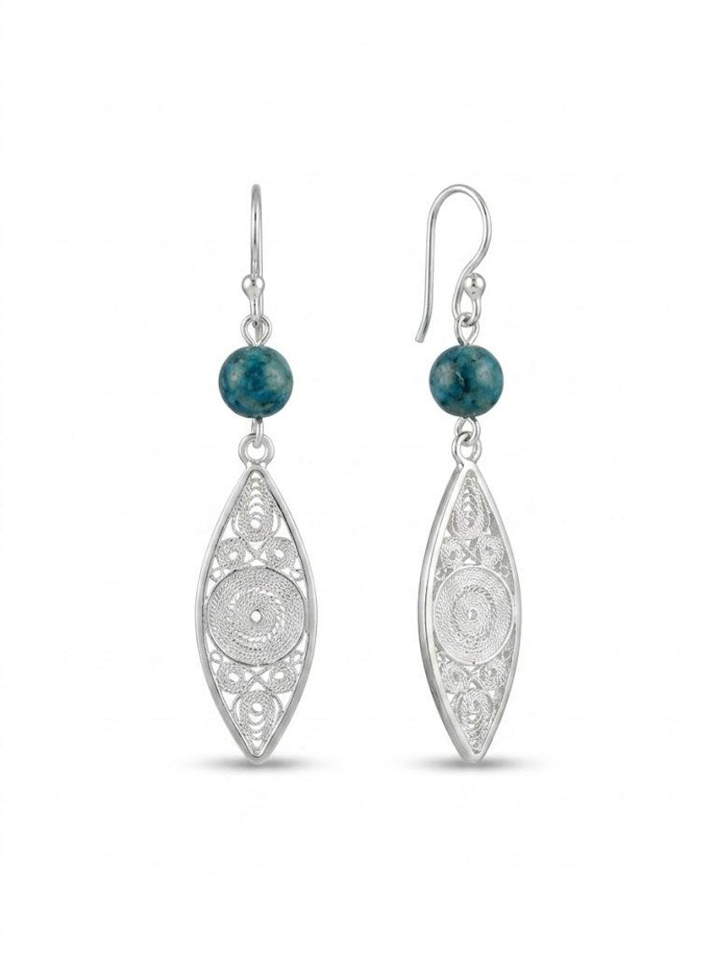 A pair of silver filigree dangle earrings with round dark teal blue-green beads at the top, shown on a clean white background.
