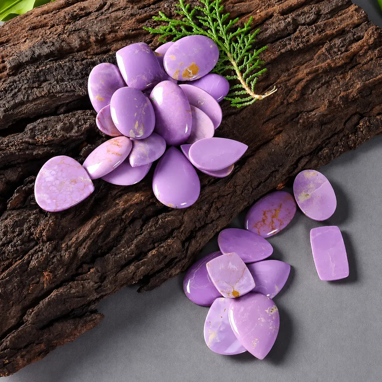 Purple gemstones on a wooden surface with green leaves