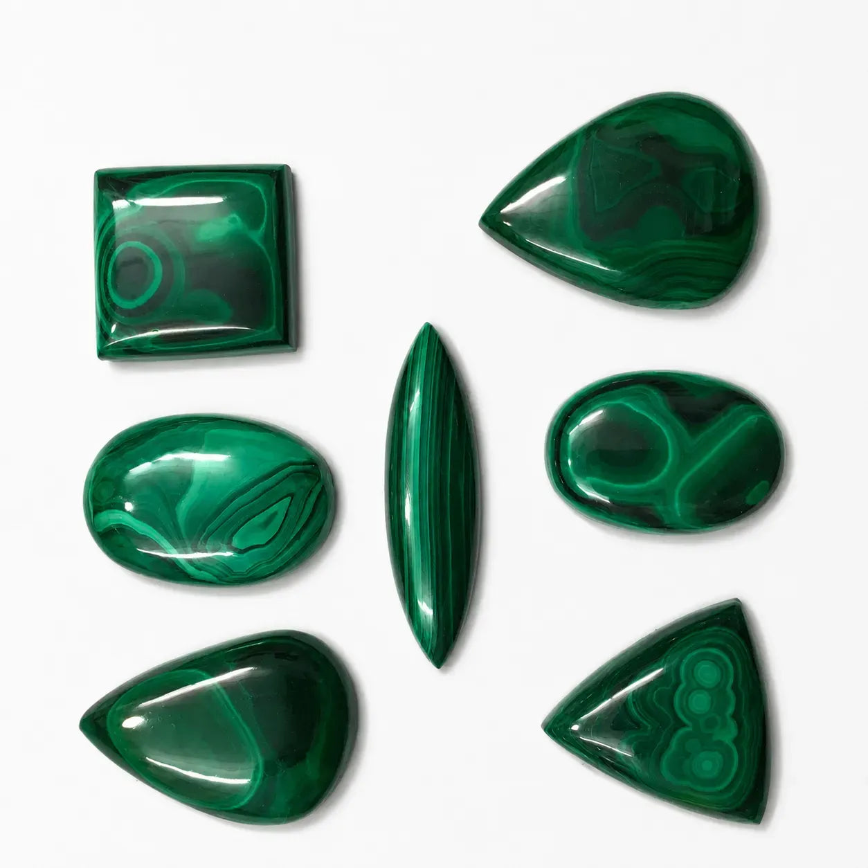 Set of green malachite stones in various shapes on a white background