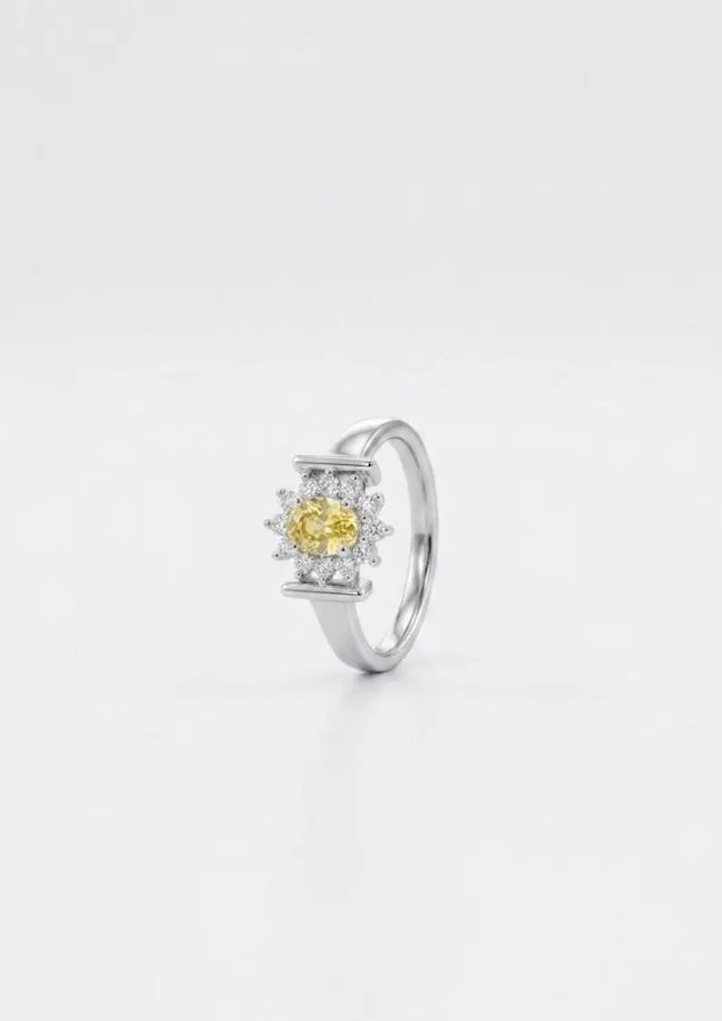 Side angle view of sterling silver ring with oval yellow cubic zirconia and sunburst halo setting